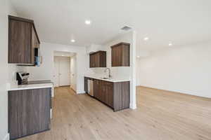 Kitchen with dark brown cabinets, stainless steel appliances, light wood-style flooring, modern cabinets, and recessed lighting