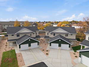 Traditional-style house featuring a shingled roof, driveway, and a residential view