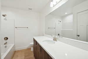 Bathroom with shower / tub combination, light wood-style floors, and vanity