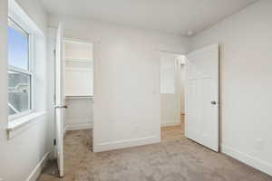 Unfurnished bedroom featuring a spacious closet and light colored carpet