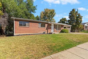Ranch-style house featuring a front lawn, brick siding, driveway, and covered porch