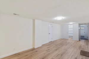 Below grade area featuring light wood-type flooring and a textured ceiling