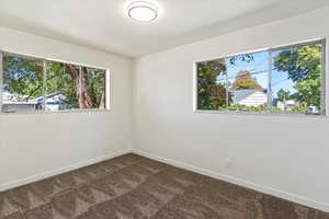 Spare room with baseboards and dark carpet
