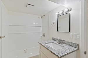 Full bathroom with vanity, tub / shower combination, and a textured ceiling