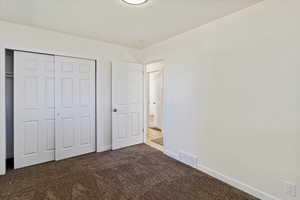 Unfurnished bedroom featuring dark colored carpet and a closet