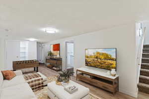 Living area with stairway, light wood-style flooring, and a textured ceiling