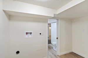 Laundry area featuring light wood-style floors, hookup for an electric dryer, washer hookup, and a textured ceiling