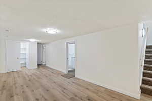 Basement featuring stairs, a textured ceiling, and light wood-style floors