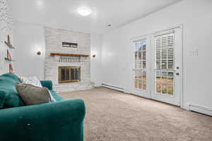 Carpeted living room with a fireplace and a baseboard heating unit