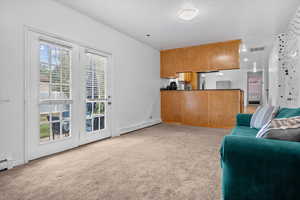 Kitchen with dark countertops, open floor plan, baseboard heating, light carpet, and brown cabinets