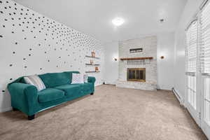 Living area featuring a brick fireplace, carpet floors, and a baseboard heating unit