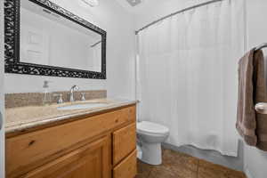 Full bathroom featuring vanity, shower / bath combo, and dark tile patterned flooring