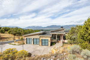View of front facade featuring stone siding, a mountain view, driveway, a garage, and a chimney