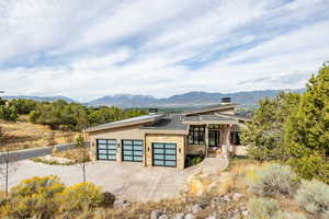 View of front facade featuring stone siding, a mountain view, driveway, a garage, and a chimney
