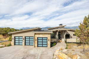 Modern home featuring stone siding, concrete driveway, an attached garage, and a mountain view