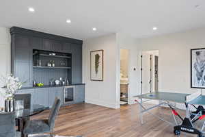 Indoor wet bar featuring recessed lighting, light wood-style floors, open shelves, wine cooler, and dark stone counters