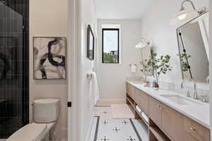 Bathroom featuring double vanity, light tile patterned floors, and tiled shower