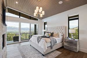 Bedroom featuring a mountain view, lofted ceiling, access to exterior, wooden ceiling, and a chandelier