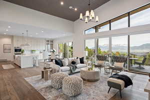 Living area featuring a mountain view, dark wood-style floors, recessed lighting, a towering ceiling, and a chandelier