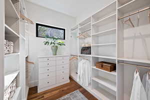 Walk in closet with dark wood-style flooring