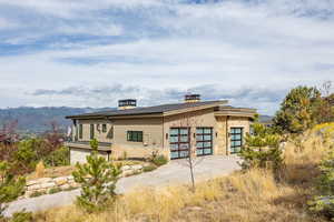 Back of property with stone siding, driveway, and a mountain view