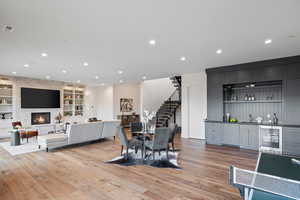 Dining room featuring stairway, light wood-type flooring, bar area, built in features, and a stone fireplace