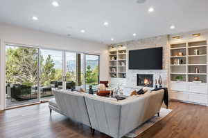 Living room featuring recessed lighting, a fireplace, hardwood / wood-style flooring, and built in features