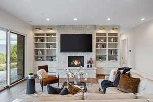 Living room with a fireplace, wood finished floors, recessed lighting, a mountain view, and built in shelves