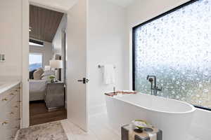 Bathroom with connected bathroom, a soaking tub, vanity, wood ceiling, and lofted ceiling