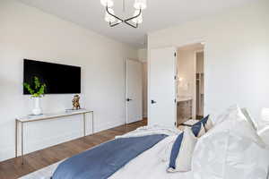 Bedroom featuring wood finished floors, a chandelier, and connected bathroom