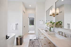 Bathroom featuring light tile patterned flooring, a freestanding tub, double vanity, a stall shower, and recessed lighting