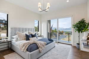 Bedroom with wood finished floors, access to outside, a chandelier, a mountain view, and recessed lighting