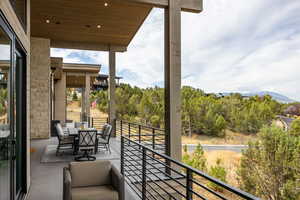 Balcony featuring outdoor dining area and view of scattered trees