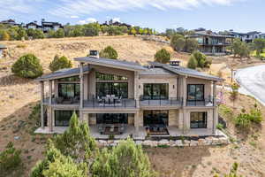 Rear view of property featuring stone siding, a patio area, a chimney, and outdoor dining area