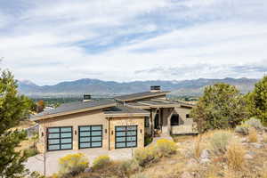 View of front of home with stone siding, a mountain view, an attached garage, and driveway