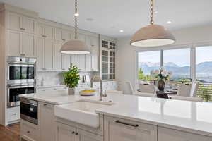 Kitchen with stainless steel appliances, a mountain view, decorative light fixtures, light stone countertops, and recessed lighting