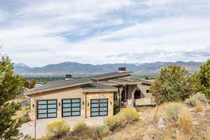View of front of home with stone siding, a mountain view, an attached garage, and driveway