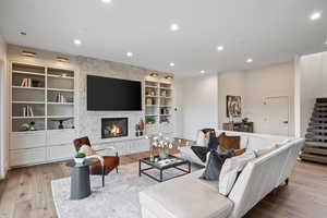 Living area with stairs, recessed lighting, light wood-style floors, and a stone fireplace