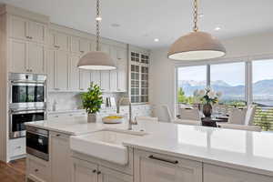 Kitchen with appliances with stainless steel finishes, a mountain view, decorative light fixtures, light stone countertops, and decorative backsplash