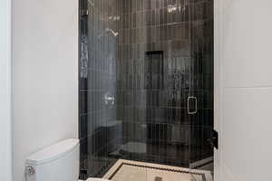 Full bathroom featuring a stall shower and toilet