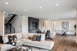 Living room with recessed lighting, wood finished floors, and stairs