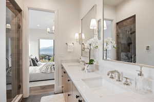 Ensuite bathroom featuring double vanity, a shower stall, and dark wood-style flooring
