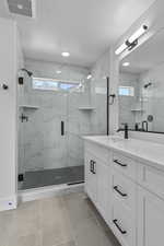 Bathroom with vanity, a marble finish shower, a textured ceiling, and light tile patterned flooring