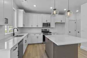 Kitchen featuring white cabinetry, light stone countertops, stainless steel appliances, recessed lighting, and a center island