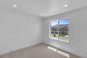 Carpeted spare room featuring a residential view and recessed lighting