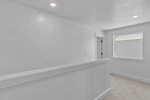 Hallway with light colored carpet and recessed lighting