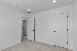 Unfurnished bedroom with light colored carpet and recessed lighting