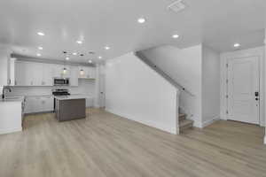 Kitchen with white cabinetry, recessed lighting, light wood-type flooring, pendant lighting, and a kitchen island