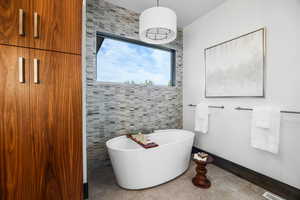 Full bathroom with a freestanding tub, tile walls, and light tile patterned flooring