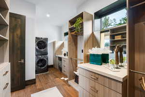 Laundry area featuring light wood-type flooring, stacked washer / drying machine, and recessed lighting